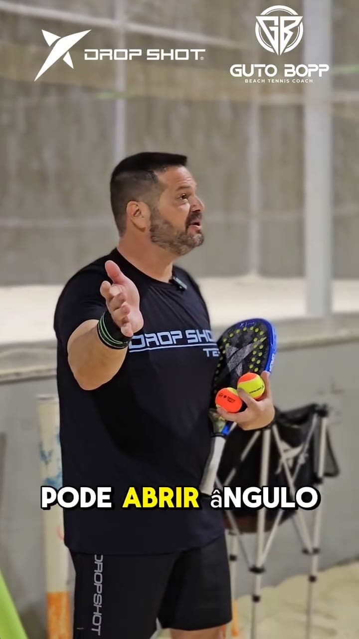 Guto Bopp com raquete e bolas na mão, explicando um golpe durante a aula
